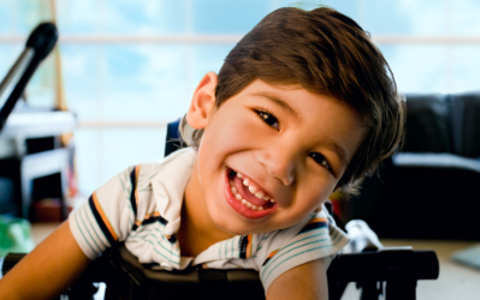 Little boy in wheelchair smiling.