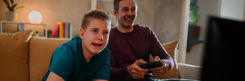 Foster dad and son playing a computer game sat on the sofa